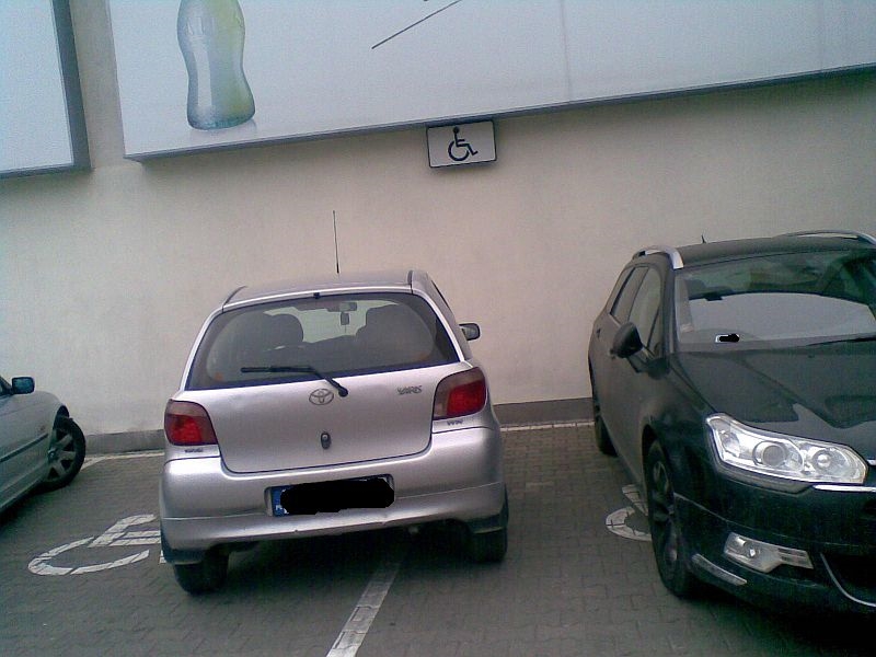 Nieprawidłowo zaparkowany samochód zajmujacy jednocześnie dwa miejsca dla osób z niepełnosprawnością