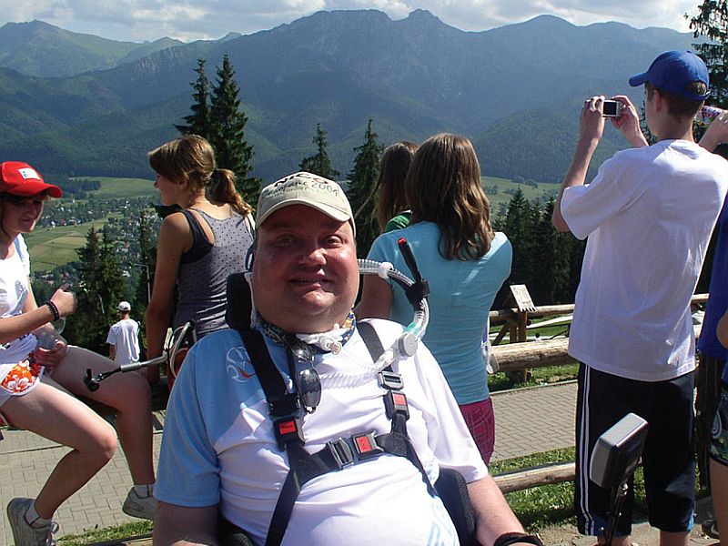 Uśmiechnięty Janusz Świtaj, za nim widok na góry