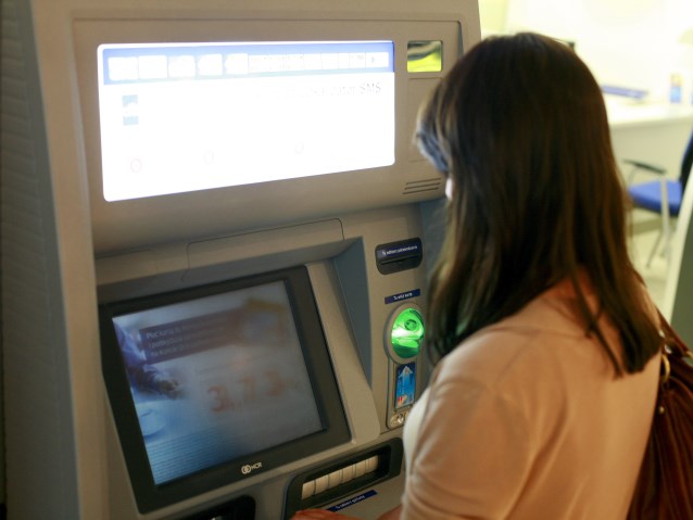 kobieta wypłaca pieniądze z bankomatu