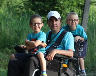 Mariusz Mączka siedzi na wózku ze swoimi dwoma synkami