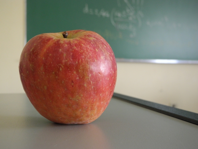 jabłko na stoliku, w tle tablica szkolna