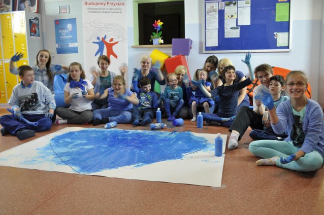 kobiety ze Stowarzyszenia bawią się z dziećmi - na zdjęciu po namalowaniu rękami niebieską farbą na papierze ogromnego serca