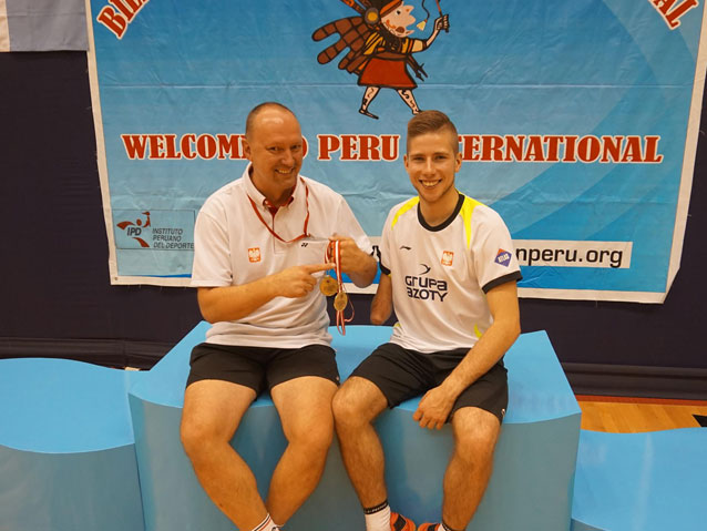 trener i Bartek Mróz siedzą obok siebie, trzymając w dłoniach medale