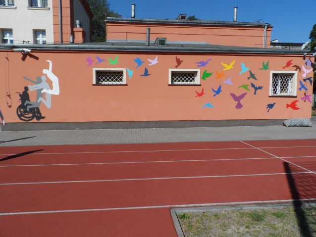 mural - z lewej strony osoba na wózku, która wstaje i skacze, na środku i z prawej kolorowe ptaki