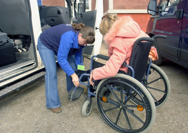 kobieta pomaga w przygotowaniu wózka inwalidzkiego do wjazdu do samochodu