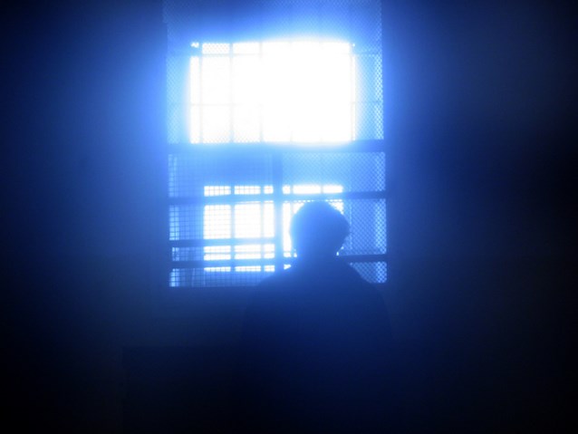mężczyzna wygląda za okno więzienia z kratami