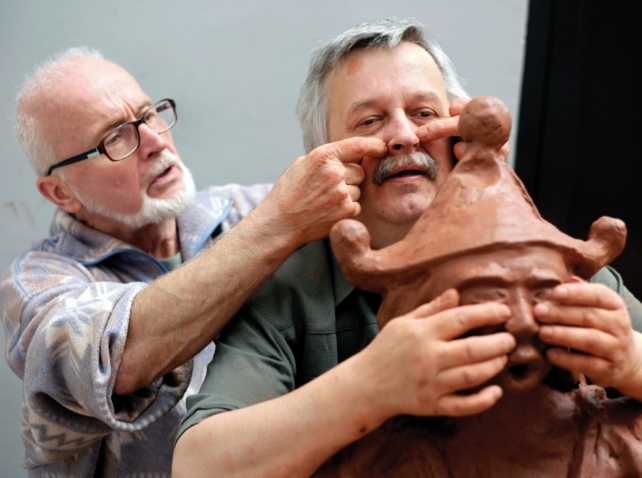głuchoniewidomy mężczyzna dotyka rzeźby, z kolei pełnosprawny mężczyzna pokazuje mu na jego ciele czego dotyka