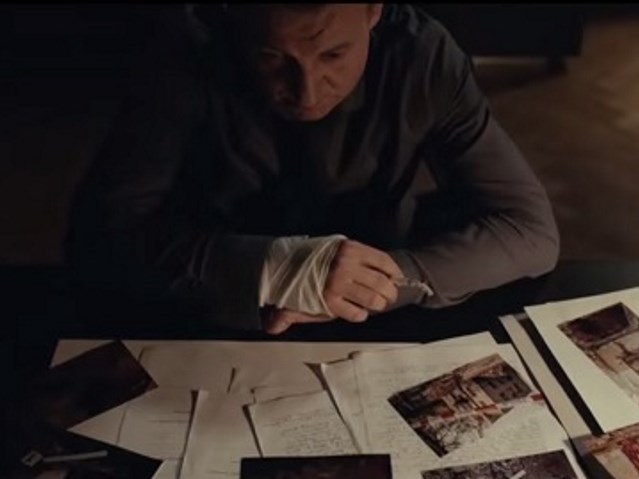 kadr z filmu - prokurator pochylony nad biurkiem pełnym notatek z zabójstwa