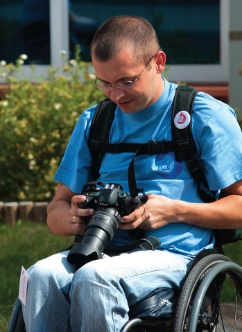 Adam Kujawa ustawia na kolanach aparat fotograficzny