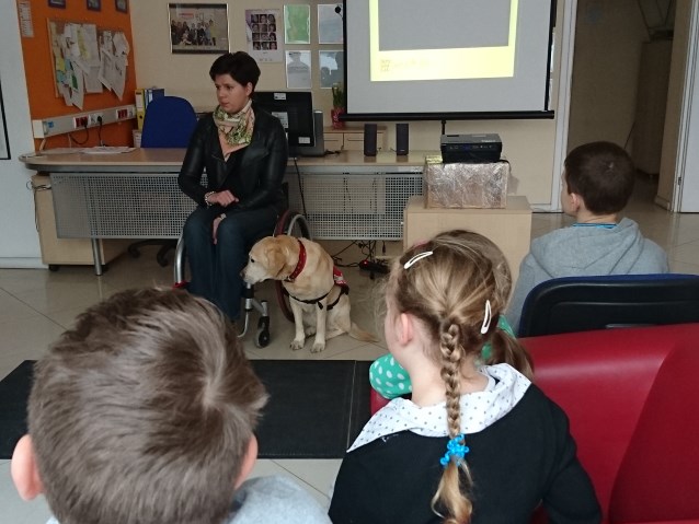 dzieci słuchają w Centrum Integracja w Gdyni szkoleniowca, kobiety na wózku z psem asystentem