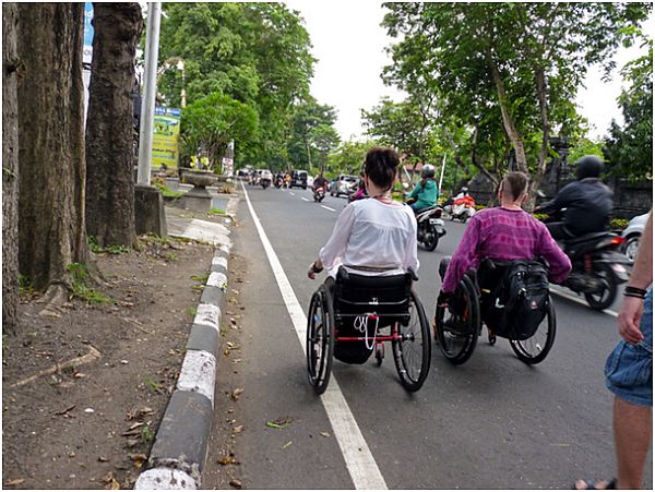 Kobieta i mężczyzna na wózkach na ulicy wśród skuterów