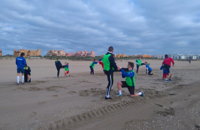 ćwiczący na plaży piłkarze 
