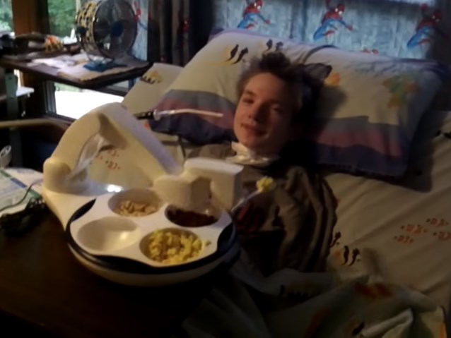 robot Obi karmi sparaliżowanego chłopca leżącego w łóżka