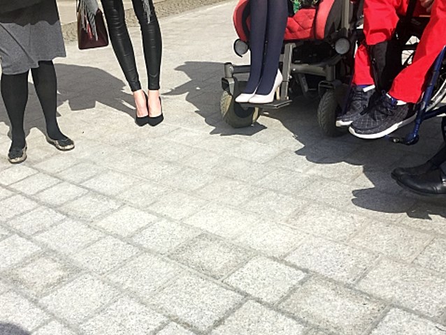 nogi osób na szpilkostradzie: kobiety na szpilkach i koła wózków