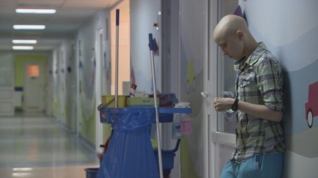 chłopiec bez włosów stoi na korytarzu szpitala