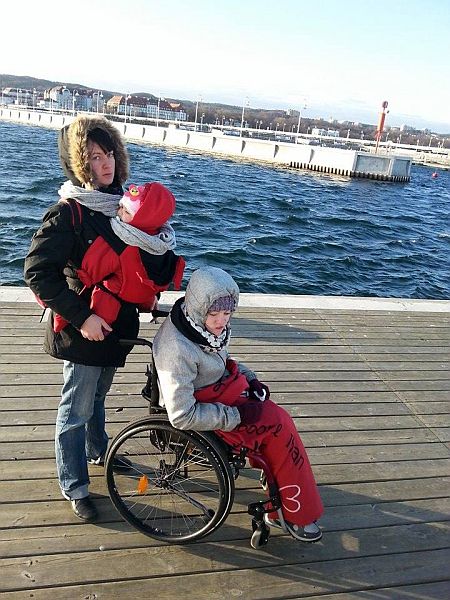 Agnieszka Suszko na nabrzeżu z dwójką swoich dzieci, w tym dziewczyną siedzącą na wózku