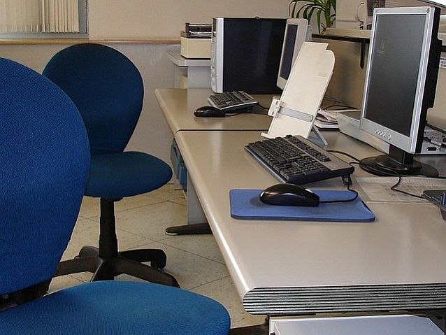 Puste krzesła obrotowe przy biurkach z komputerami