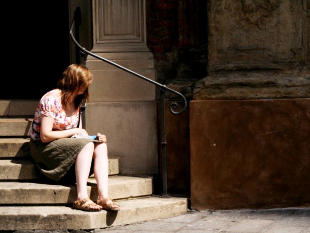 dziewczyna siedzi na schodach przed starym budynkiem