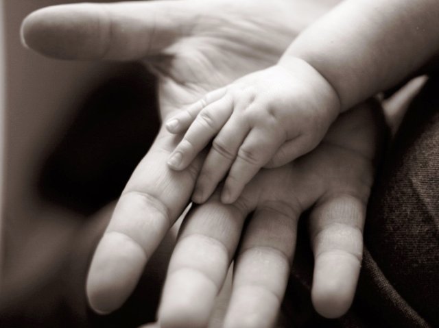 dłoń dziecka leży na dłoni rodzica
