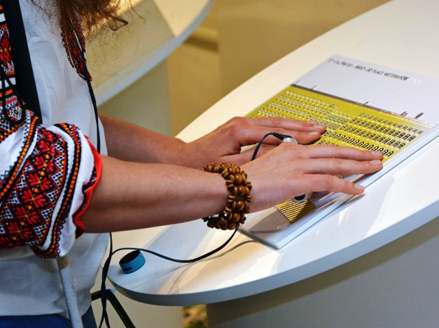 kobieta czyta w brailu coś w muzeum praskim