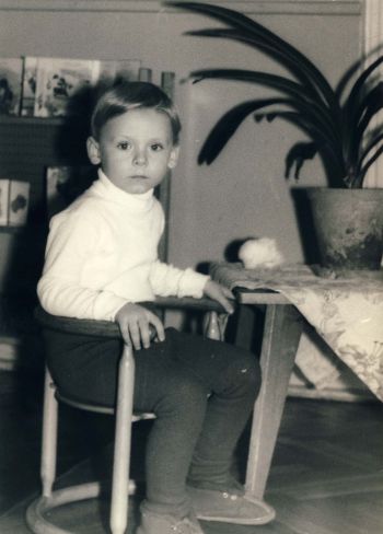 Czarno-białe zdjęcie małego Piotra Pawłowskiego, siedzącego na krzesełku