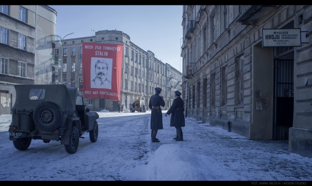 widok na ulicę, na budynku zawieszany jest wielki plakat z podobizną Stalina i napisem: Niech żyje towarzysz Stalin