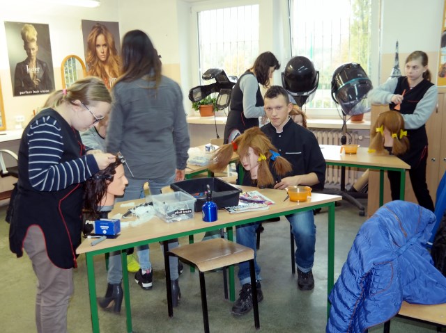 uczniowie uczą się robić fryzury na włosach manekinów