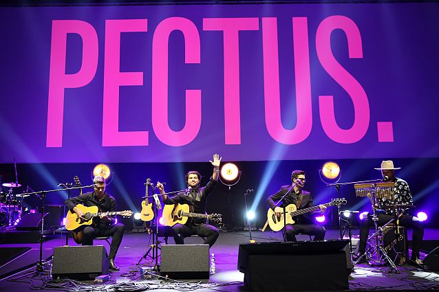 Czterech członków zespołu siedzi na scenie, trzech z nich gra na gitarach, czwarty na instrumentach perksyjnych. Nad nimi ogromny napis: Pectus.