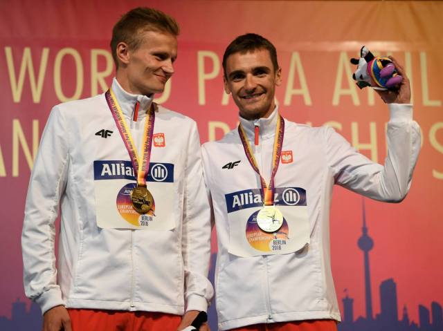 Aleksander Kossakowski z przewodnikiem Krzysztofem Wasilewskim stoją na podium ze złotymi medalami