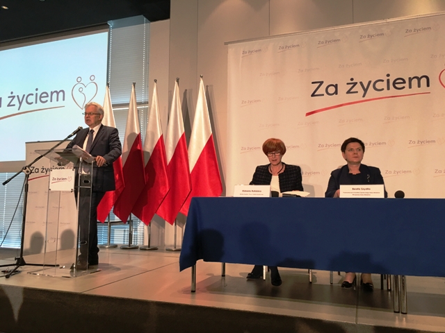 Od lewej na mównicy pełnomocnik rządu ds. osób niepełnosprawnych wiceminister Krzysztof Michałkiewicz, przy stole siedzą minister Rafalska i wicepremier Szydło