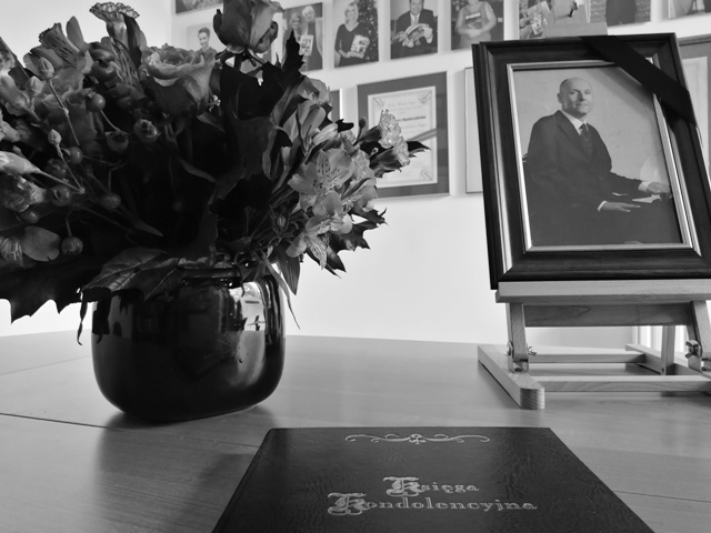 Księga kondolencyjna leży na stole. Obok niej bukiet kwiatów i zdjęcie Piotra Pawłowskiego