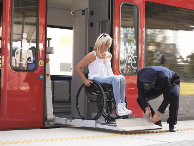 konduktor pomaga rozłożyć rampę przy wyjeździe kobiety na wózku z pociągu