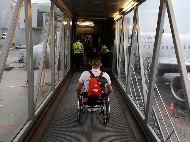 Mężczyzna na wózku w rękawie prowadzącym do samolotu na lotnisku