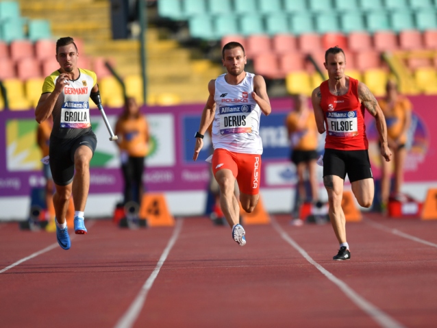 Michał Derus biegnie po bieżni, obok niego dwóch zawodników