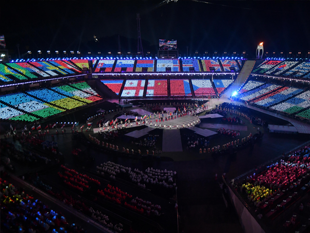 Marsz przedstawicieli 49 państw z flagami przez płytę stadionu. Na trybunach znajdują się wizualizacje flag państw