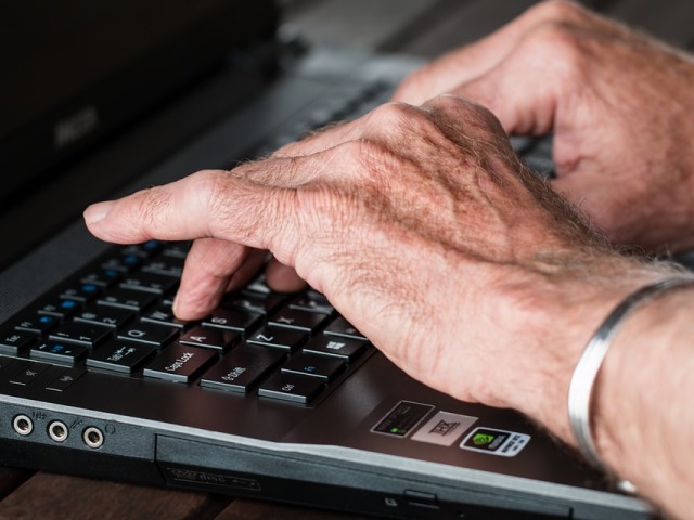 ręce seniora pisza na klawiaturze komputera