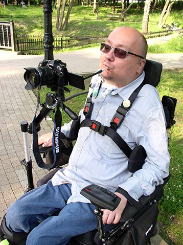 Janusz Świtaj fotografuje ustami używając patyczka, by nacisnąć w zamontowanym na wózku aparacie przycisk