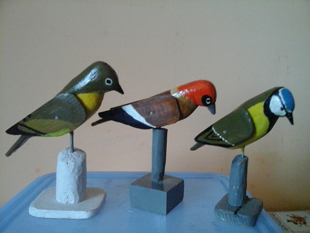 Trzy kolorowe ptaszki wystrugane w drewnie