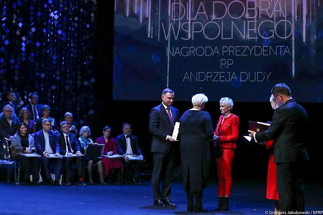 Scena. Ewa Pawłowska wręcza nagrodę Ewie Błaszczyk, obok nich stoi prezydent Andrzej Duda