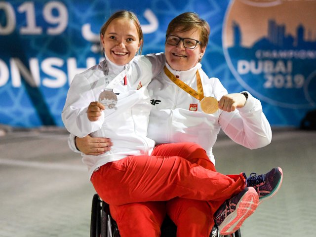 W Dubaju Lucyna Kornobys na wózku na jej kolanach Renata Śliwińska obie uśmiechnięte trzymają w dłoniach wiszące na szyi medale
