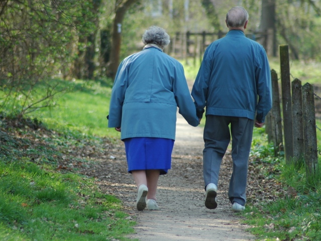 starszy kobieta i mężczyzna idą trzymając się za rękę widoczni tyłem