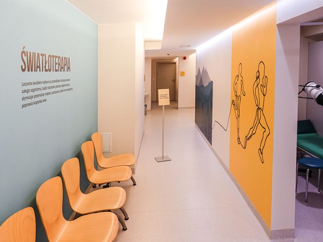 ustroń korytarz po lewej na ścianie napis światłoterapia i krzesła pod scianą wszystko w pastolowych kolorach