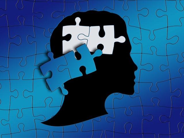 grafika na tle niebieskich puzzli rysunek głowy z której wypadły dwa puzzle