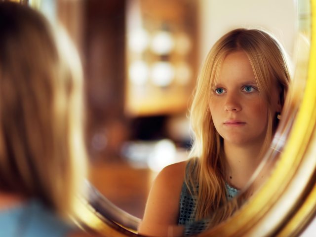 dziewczyna przegląda się w lustrze widać jej odbicie