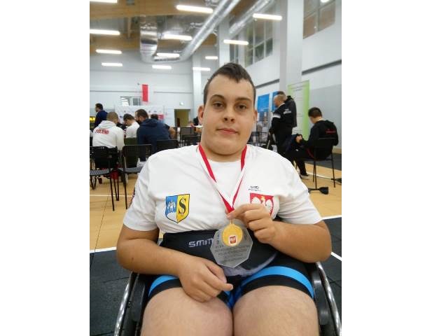 Mateusz Leśniewski w sportowym stroju na wózku z medalem na szyi