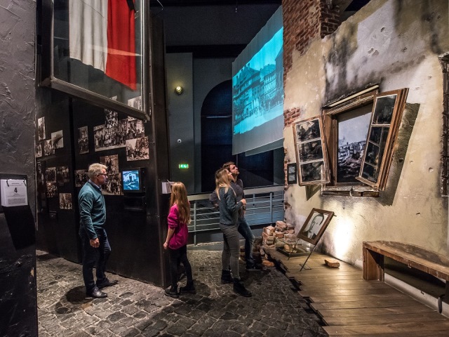 kilka osób ogląda eksponaty w muzeum powstania warszawskiego