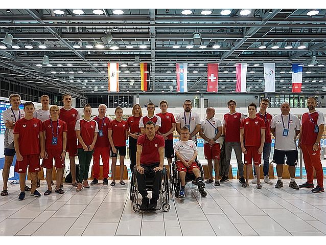 Reprezentanci Polski w pływaniu pozują do grupowego zdjęcia koło basenu