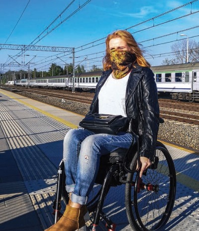 Julita Kruczkowska z długimi włosami na wózku na peronie pkp chustka na nosie i ustach