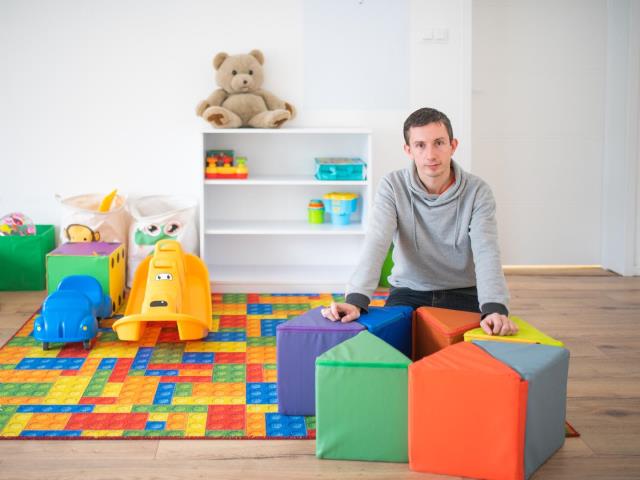 Tomasz Ciechon siedzi wśród zabawek na przedszkolnej sali