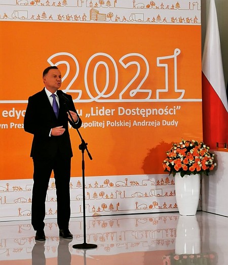 Prezydent Andrzej Duda stojąc mówi do mikrofonu